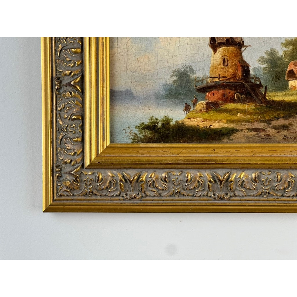 Close-up of an ornate gold frame corner showing part of an Antique Continental School Oil on Canvas Landscape with Windmill, signed “Brüguer,” circa 1880-1910, featuring greenery and figures under a cloudy sky.