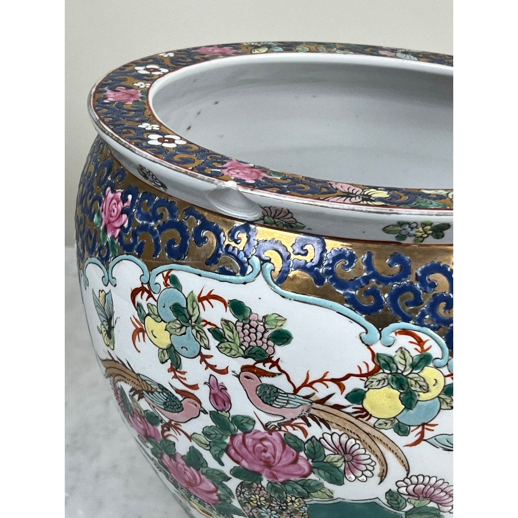A close-up of a Vintage Chinese Famille Rose Fish Bowl Signed Minicucci, hand-painted with pink roses, green leaves, birds, and gold detailing. The white porcelain bowl has a visible rim chip and displays classic famille rose vintage style.