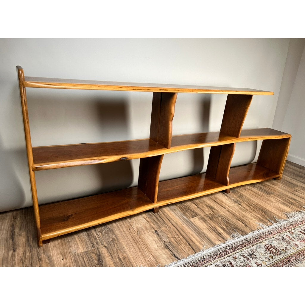 A Vintage Mid-Century Modern Style Live Edge Walnut Bookshelf with three shelves and five open compartments, finished naturally, stands on a wood floor beside a partially visible patterned rug.