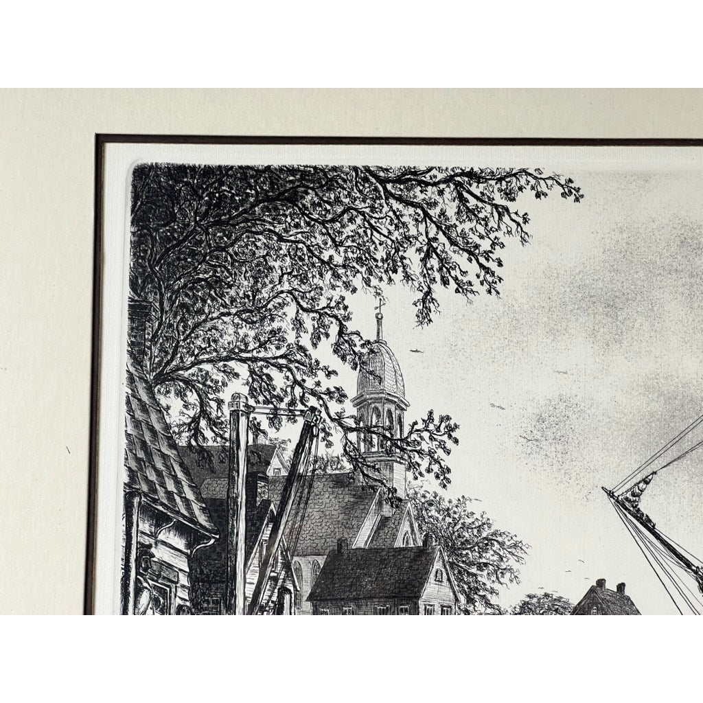 Framed etching “The Schooner” by Alan Jay Gaines depicts rooftops, a church with a domed tower, tree branches, and a sailboat mast in a detailed black and white maritime architectural scene. Brand is unknown.