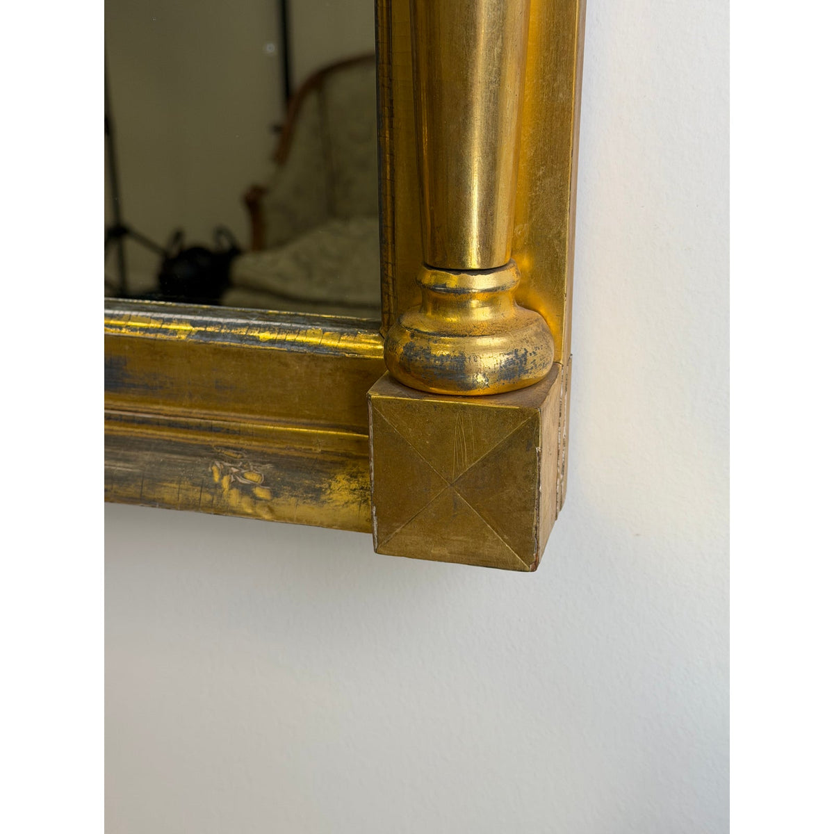 Close-up of the lower corner of an American Federal Giltwood Two-Plate Looking Glass, showing a gold-toned wooden frame with a columnar pillar detail.