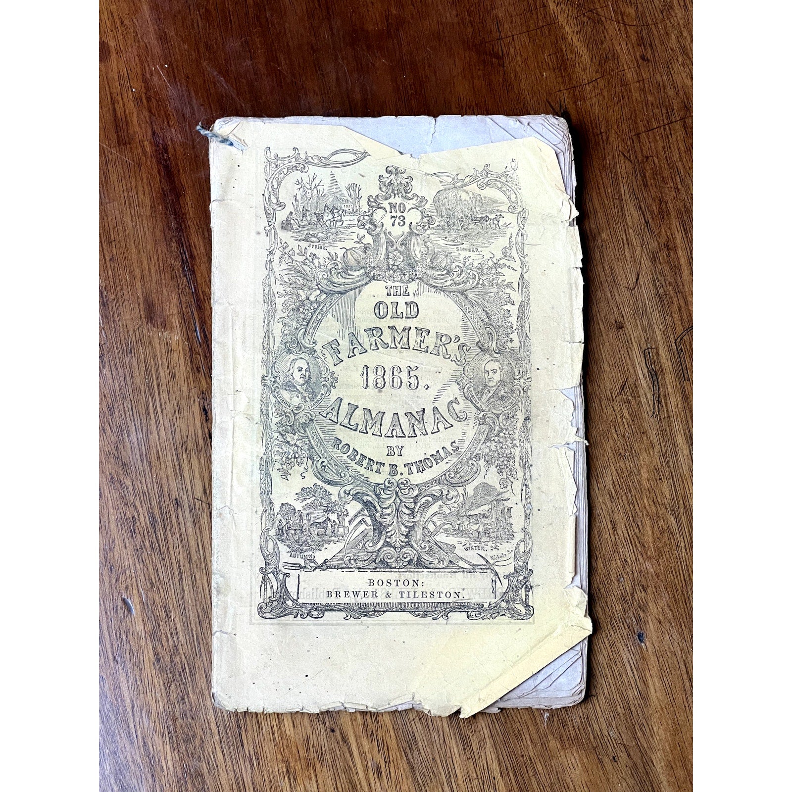 A rare Antique Set of Four Old Farmer’s Almanacs (1858, 1861, 1864 & 1865) by Robert B. Thomas sits on a wooden surface—a valuable collection of 19th-century Americana for collectors and history enthusiasts alike.