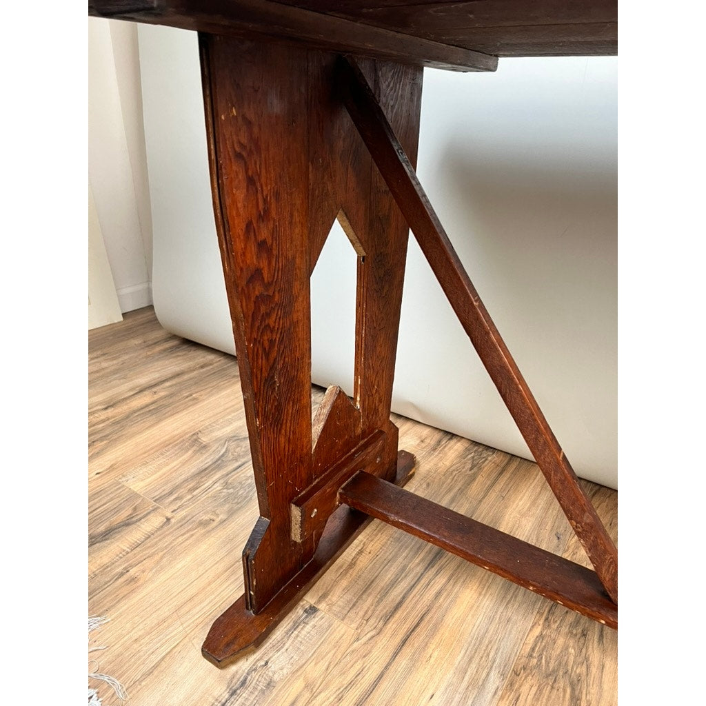 Close-up of a solid wood leg with pointed cut-out, diagonal support, and visible grain on a light floor, from an Antique Rustic Italian Fratino Trestle Table c. Late 19th Century by an unknown brand.