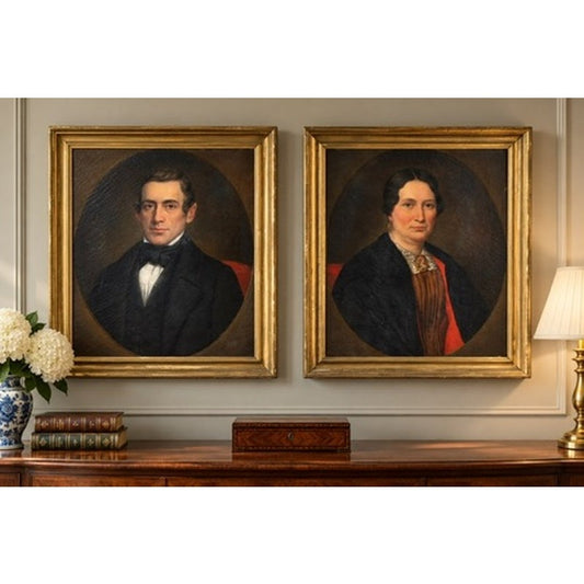 Pair of American School Oil Portraits of a Gentleman and Lady, c. 1840–1860, featuring two oval mid-19th-century oil portraits of a man and a woman in matching gold frames on a wall above a wooden console table.