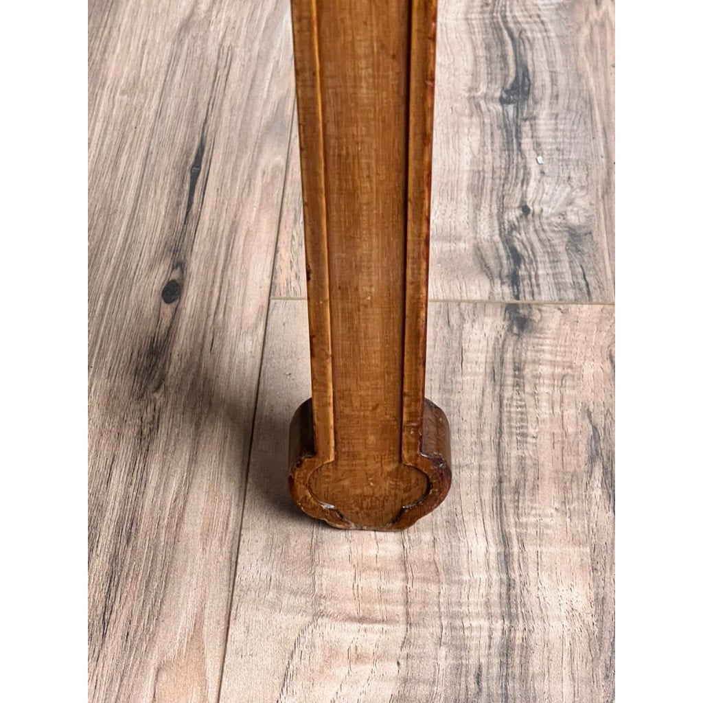 A close-up of the leg of an Antique French Directoire Style Fauteuil Open Arm Chair in Sapelle Mahogany (late 19th century), showing its rounded base, visible grain, and wear marks on a light brown wood-patterned floor.