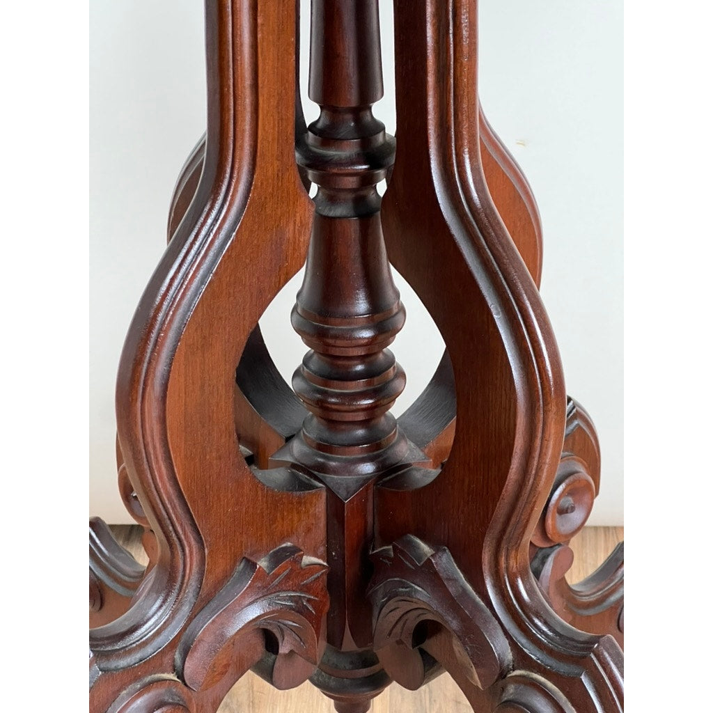 Close-up of an ornately carved dark wood leg from an Antique Victorian Walnut Lamp Stand (late 19th century), featuring curved and spiraled details, set against a plain light background and wooden floor. Brand unknown.