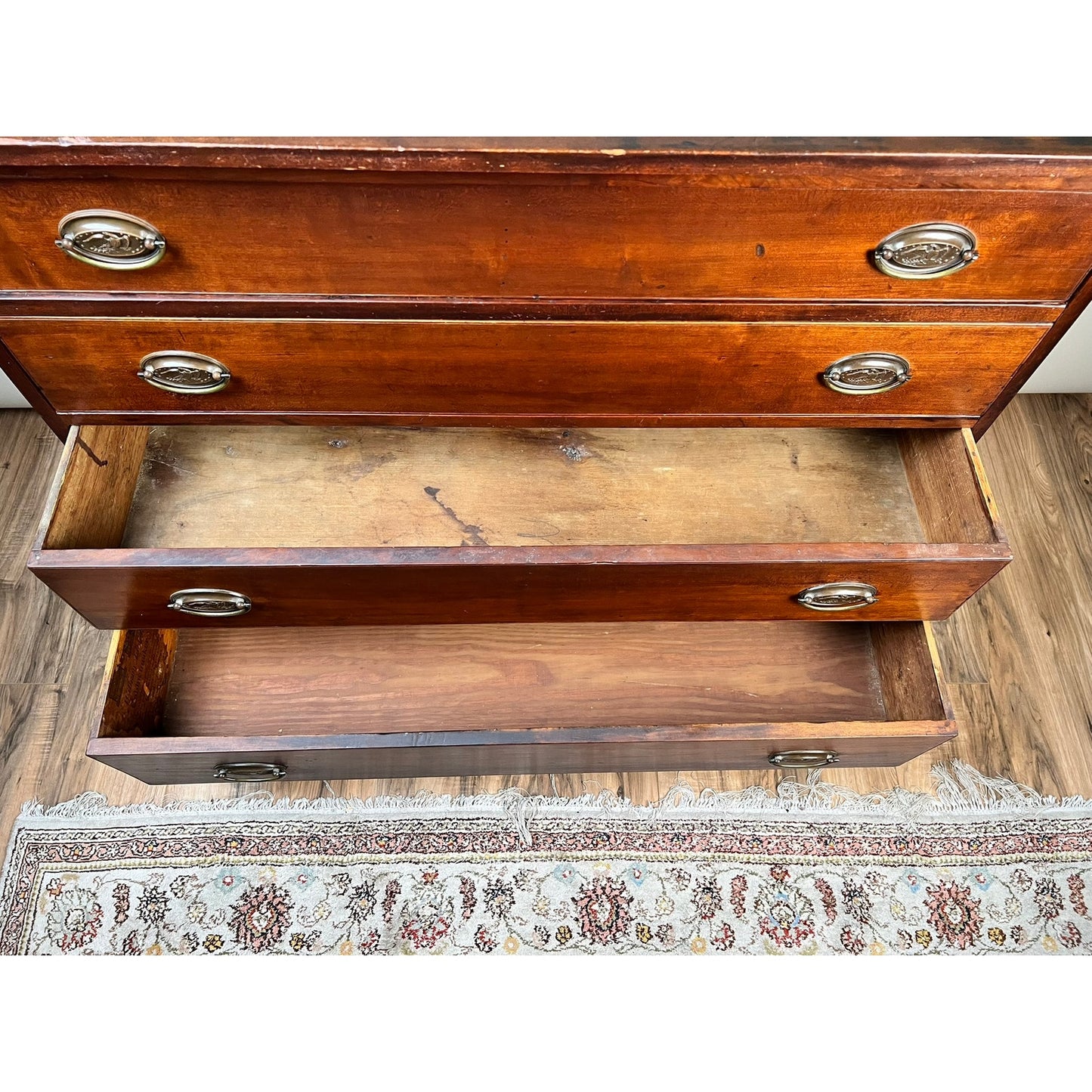 Overhead view of an open Rare Labeled William Lloyd Springfield Massachusetts Federal Cherry Chest of Drawers, Circa 1800, showing two empty drawers with worn interiors. Part of a patterned rug and wood floor can be seen at the bottom.