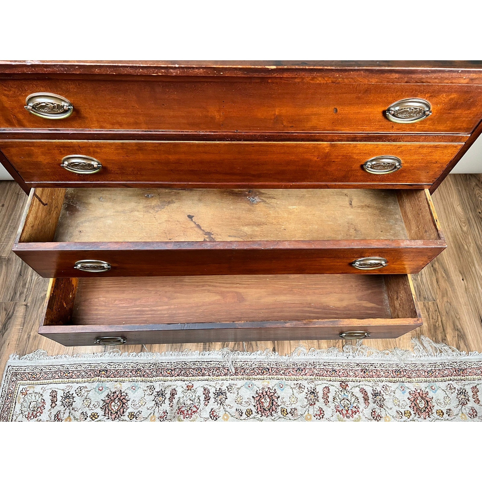 Overhead view of an open Rare Labeled William Lloyd Springfield Massachusetts Federal Cherry Chest of Drawers, Circa 1800, showing two empty drawers with worn interiors. Part of a patterned rug and wood floor can be seen at the bottom.