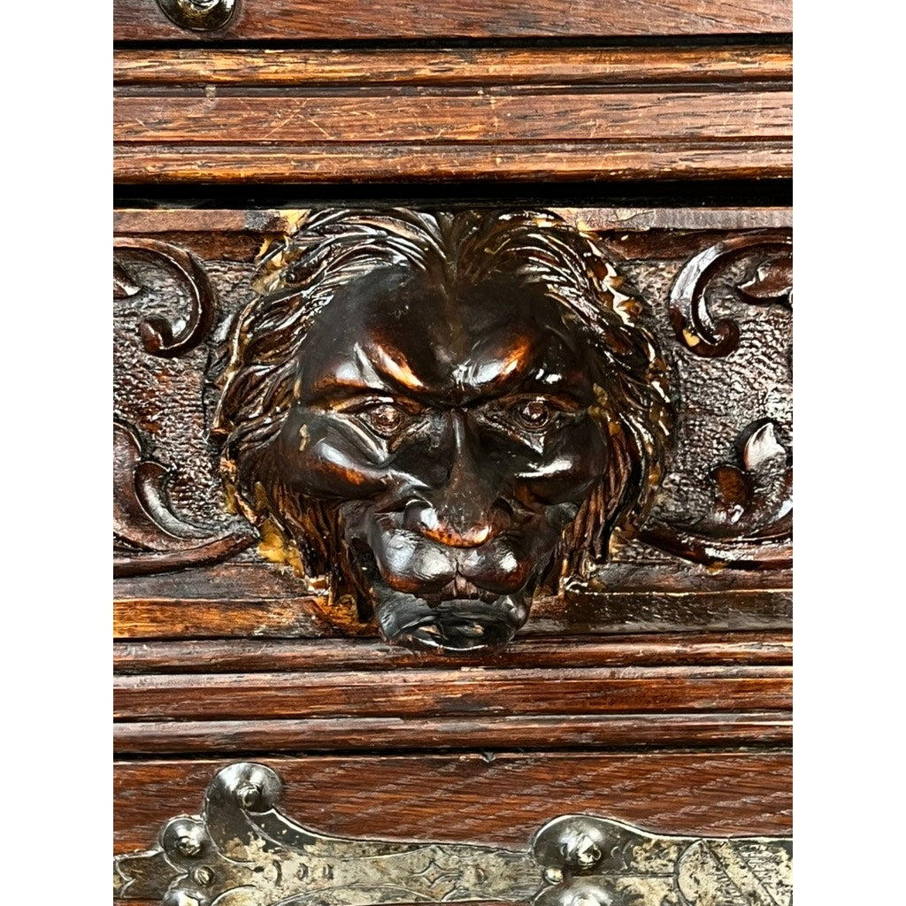 Close-up of a detailed wooden knight’s head carving with an intense expression, set in an antique 19th-century French Breton-style carved oak cabinet featuring ornate scrollwork and deeply carved knights. Brand: None/Unknown.