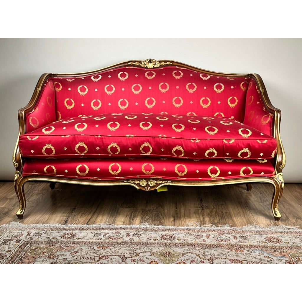 A Vintage French Regency Style Custom Upholstered Settee with red and gold circular patterned fabric, giltwood frame, and curved legs is placed on a wood floor in front of a patterned area rug. Brand: None/Unknown.