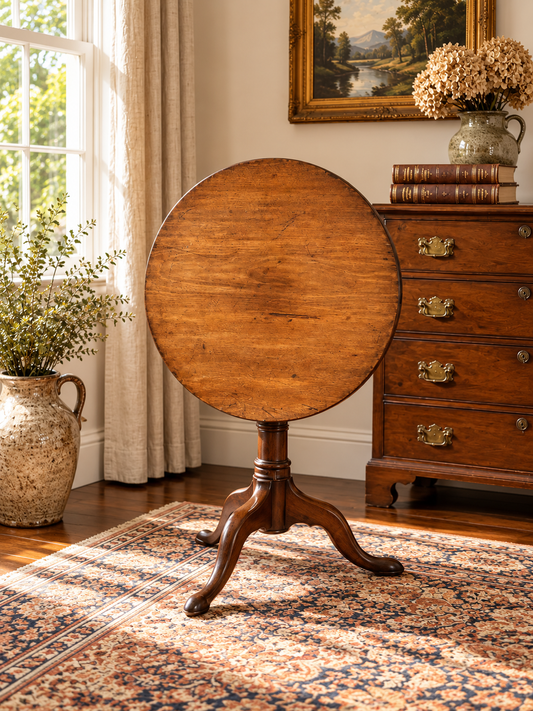An Antique Queen Anne Mahogany Birdcage Tilt Top Breakfast Table c. Early 19th Century stands on a pedestal base with three legs in a room with a chest of drawers and a floral rug.