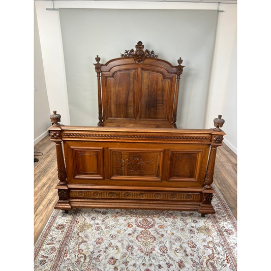 The Antique French Napoleon III Walnut Full Size Bed features intricate carvings and ornate details, set on a patterned rug in a room with hardwood floors and cream walls, exemplifying 19th-century French craftsmanship.