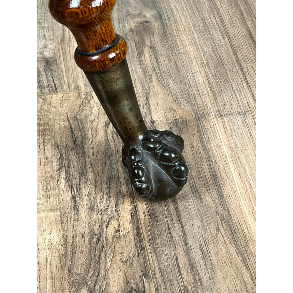 An Antique Victorian Oak Lamp Stand with bronze lions head mountings from the late 19th century rests on a wood-patterned floor, featuring a carved dark metal claw foot and decorative bronze details. Brand: None/Unknown.