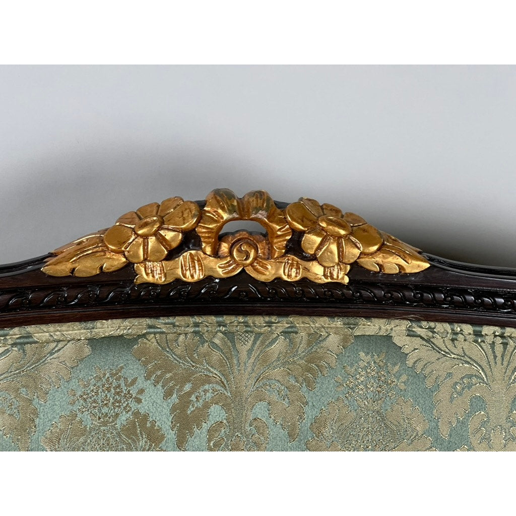 Close-up of a Vintage Louis XVI Style Settee in green damask upholstery, featuring intricate leaf motifs and gold floral carvings. Brand: Unknown.