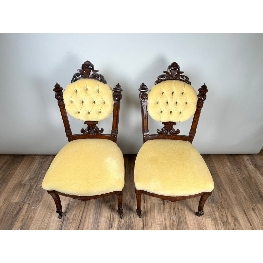 Pair of fine antique Renaissance Revival walnut side chairs, attributed to John Jelliff, Newark c. 1880, featuring ornate carved frames and yellow tufted upholstery on rounded backs and seats, displayed on a wooden floor.