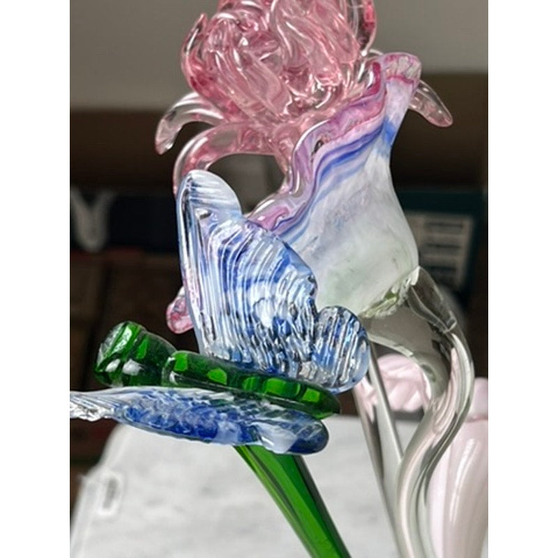 A close-up of Vintage Bouquet Murano Art Glass Long Stem Flowers and Butterflies, featuring a pink flower, blue and white butterfly, and green leaves—all delicately hand-blown with intricate swirling glass details.