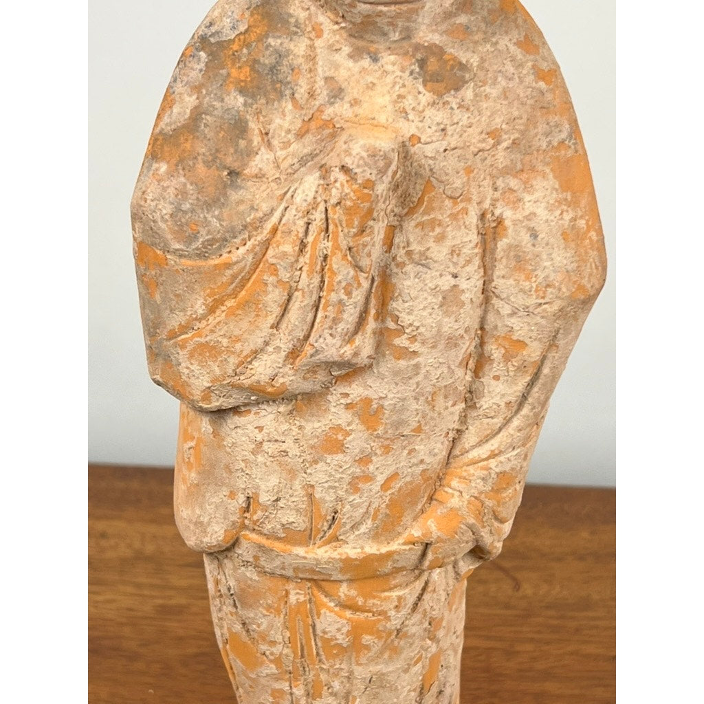 An Antique Chinese Tang Dynasty (618-907 AD) terracotta figure of a standing court lady with COA stands on a wooden surface, its weathered look and visible erosion reflecting the artistry of early Chinese sculpture.
