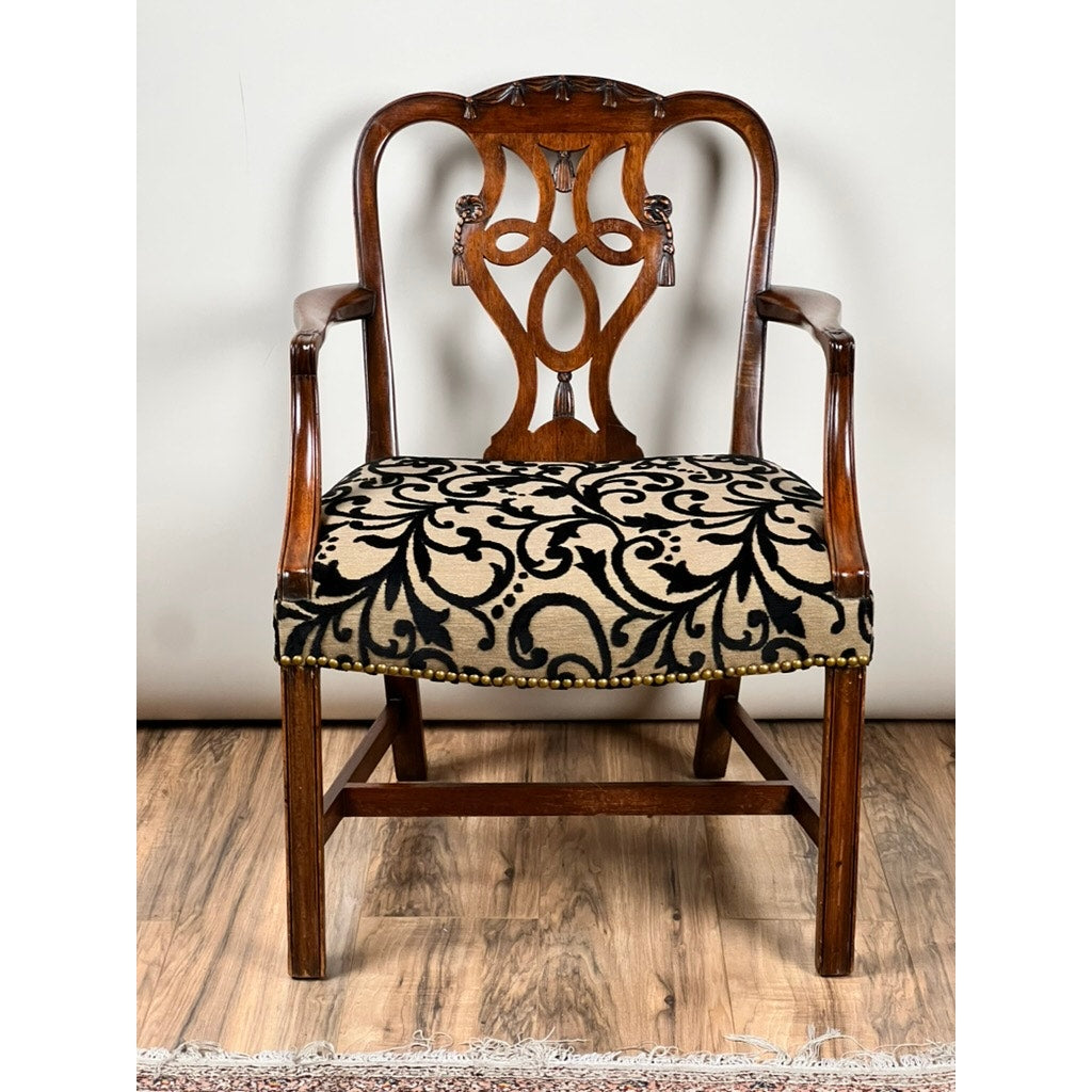Antique George III Chippendale Open Arm Chair, early 19th century, features ornate carved backrest, curved arms, and a cushioned seat in black and beige floral upholstery, set on a wooden floor with part of a small rug visible.