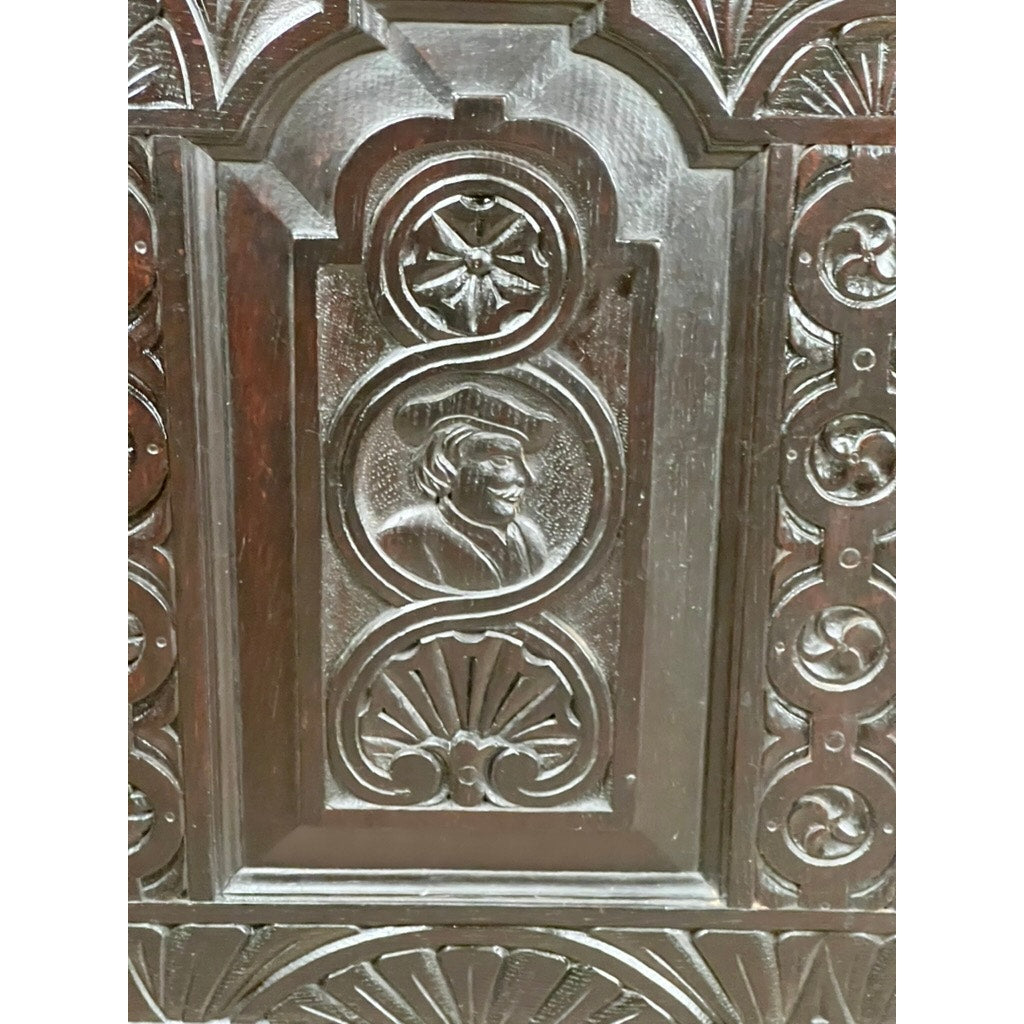 This Antique 18th Century Charles II Style Mule Chest, possibly Irish or Scottish, features dark wood panels with intricate carvings and a central raised profile portrait, evoking the refined details of 17th-century Charles II furniture.
