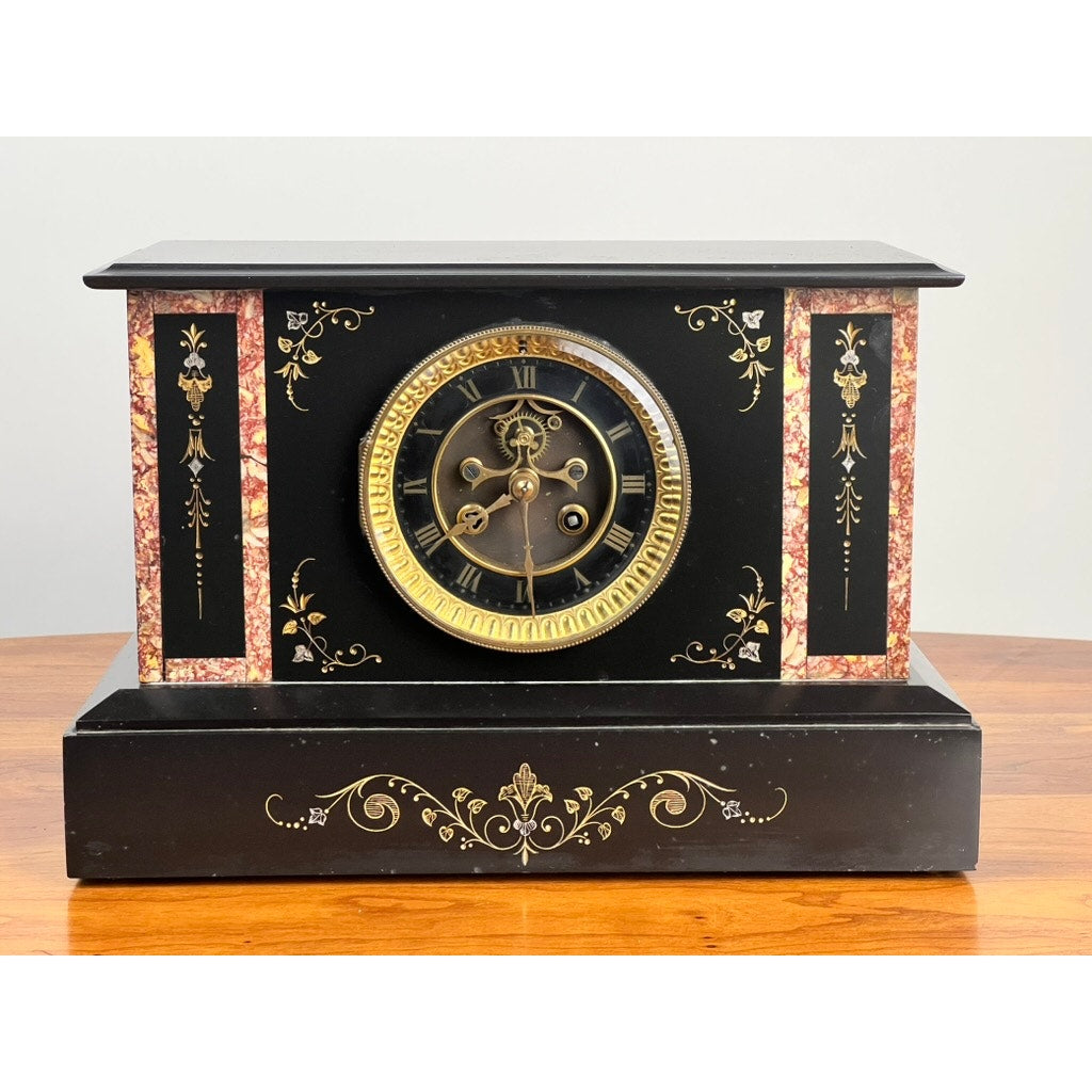 The Antique Victorian Slate Mantle Clock with Open Escapement 8 Day Time and Strike, c. late 19th century, features gold detailing, ornate floral designs, and a round Roman numeral face—an elegant vintage addition to any wooden mantel.