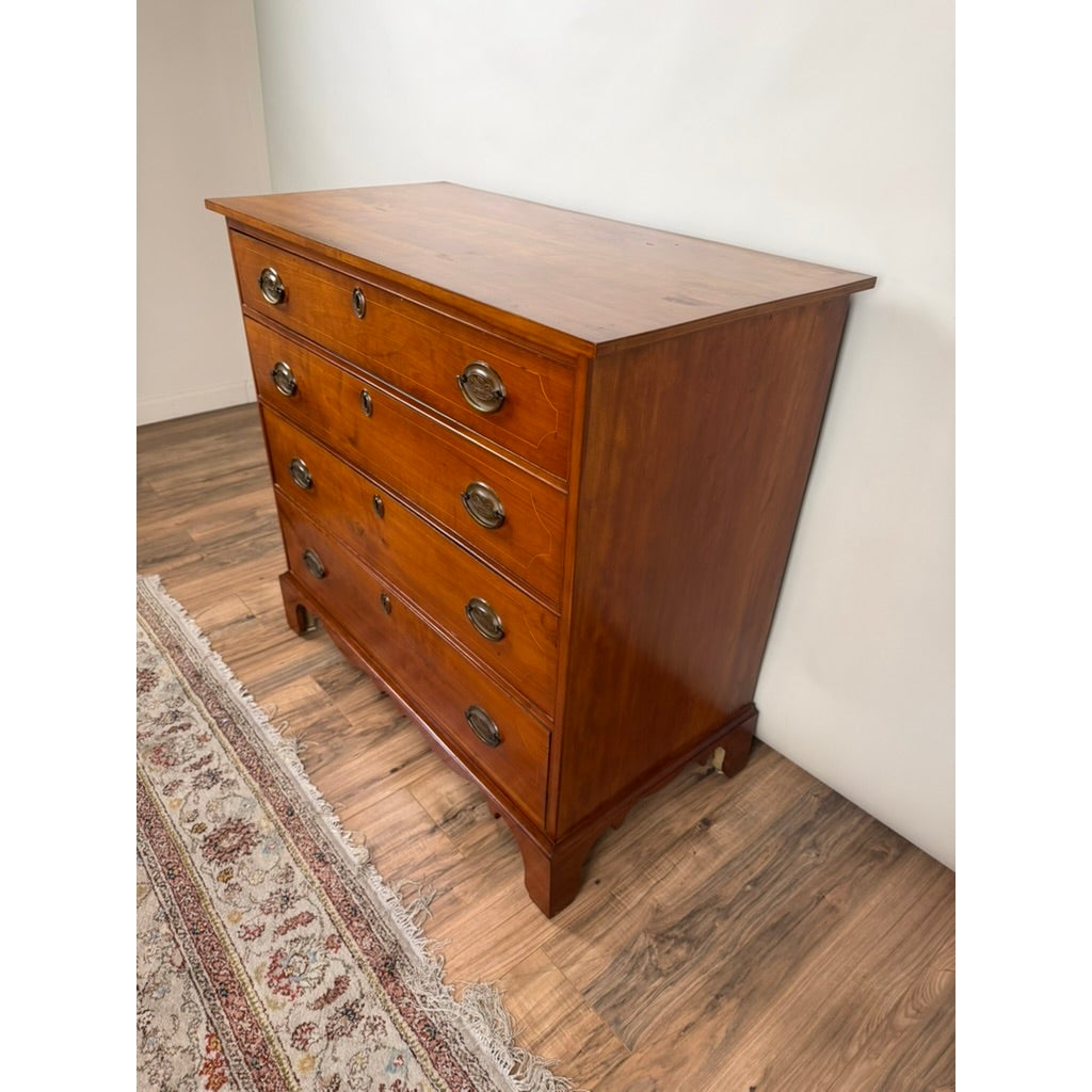 High-angle view of a Pennsylvania Federal Cherry Four-Drawer Chest with Satinwood String Inlay, featuring four drawers with brass hardware and inlay detail.