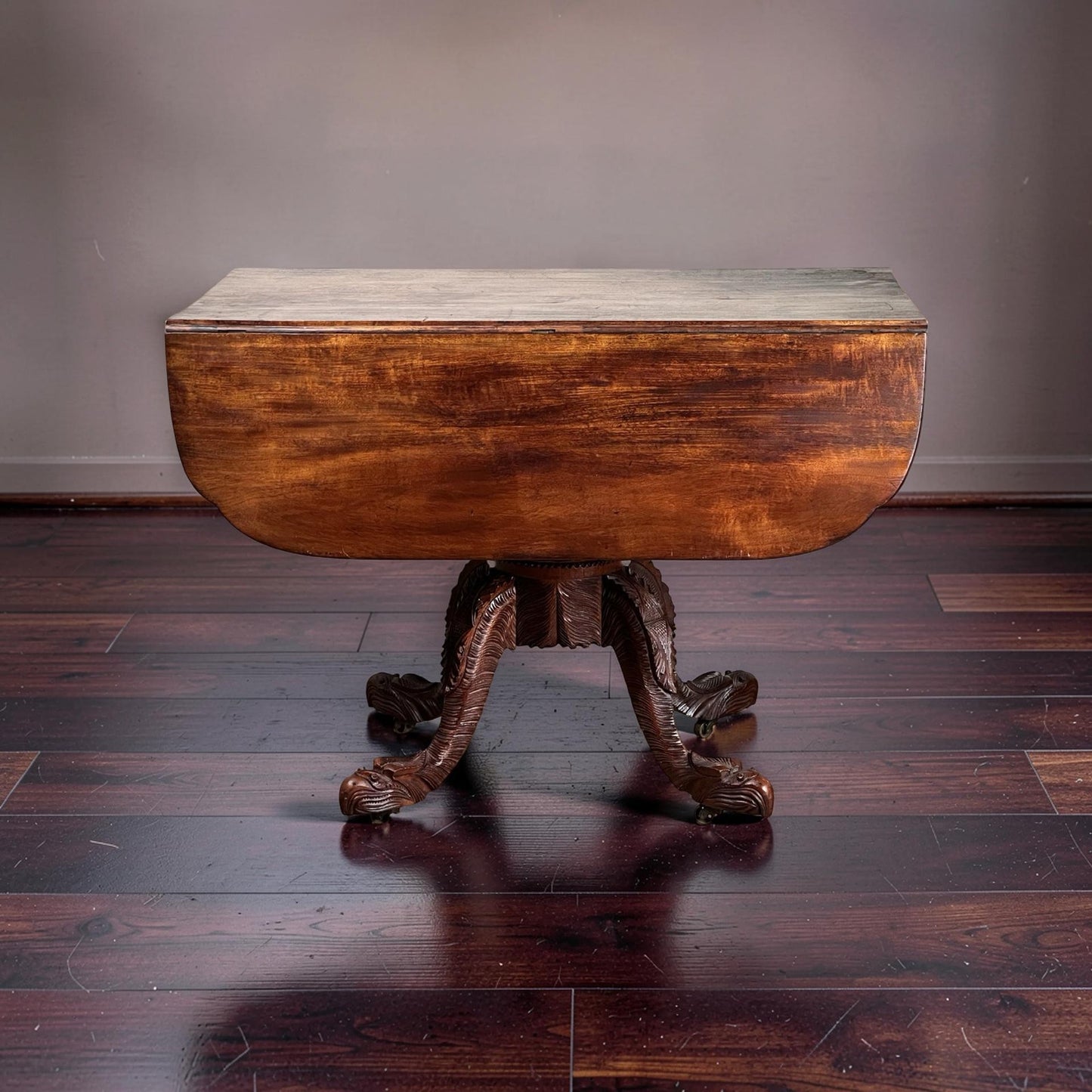 An Antique American Empire Drop Leaf Table with Great Eagle Carved Feet c. 1840 stands on a polished dark wood floor against a plain wall.
