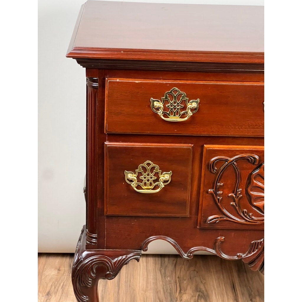 A close-up of a Vintage Solid Mahogany Chippendale Style Lowboy by Councill Craftsmen, featuring ornate carvings, two brass handles per drawer, and elegant curved legs, set on a wooden floor against a light background.