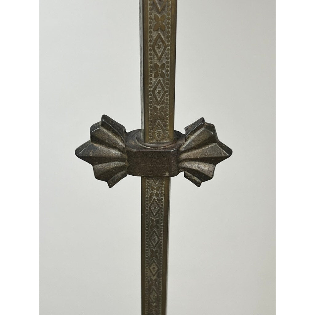 A close-up of the ornate, vertically oriented metal rod of the Antique Art Deco Cast Iron Floor Lamp by Rembrandt, featuring intricate patterns and a decorative star-shaped clamp at the center. The background is plain and light-colored.