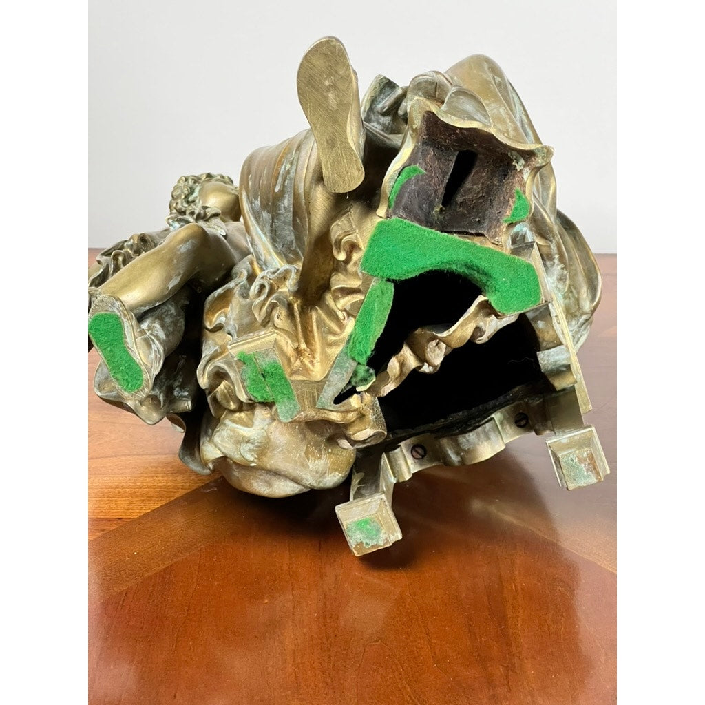 The Antique Bronze Sculpture “Teacher and Pupil” by Louis Charles Janson (signed Ch. Janson, 1865) rests on its side, revealing a hollow underside with green felt pads on the base and interior, displayed atop a wooden surface.