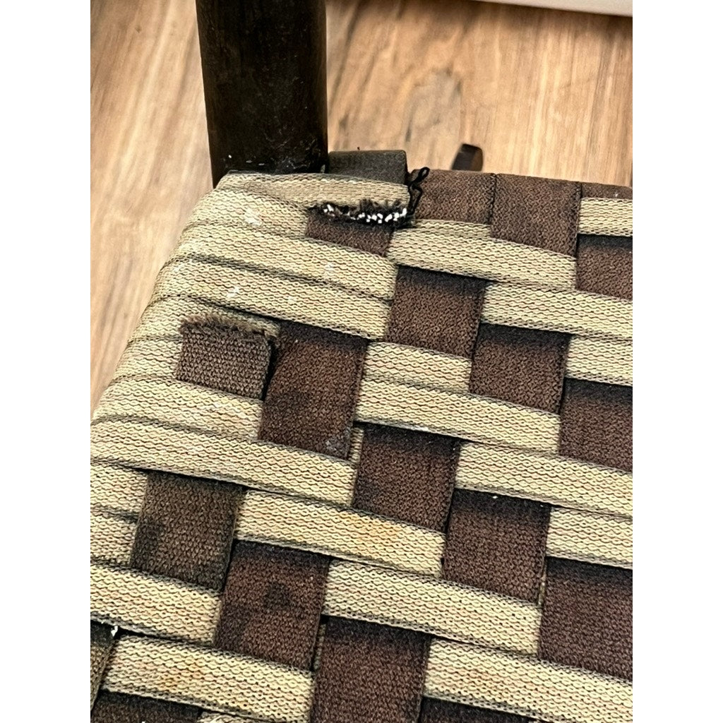 Close-up of an Antique Shaker #6 Tape Seat Rocker by Mt. Lebanon Shakers (late 19th c.) with brown and beige woven tape seat, showing fraying at the corner, a wooden leg, and wood floor below. Brand: None/Unknown.