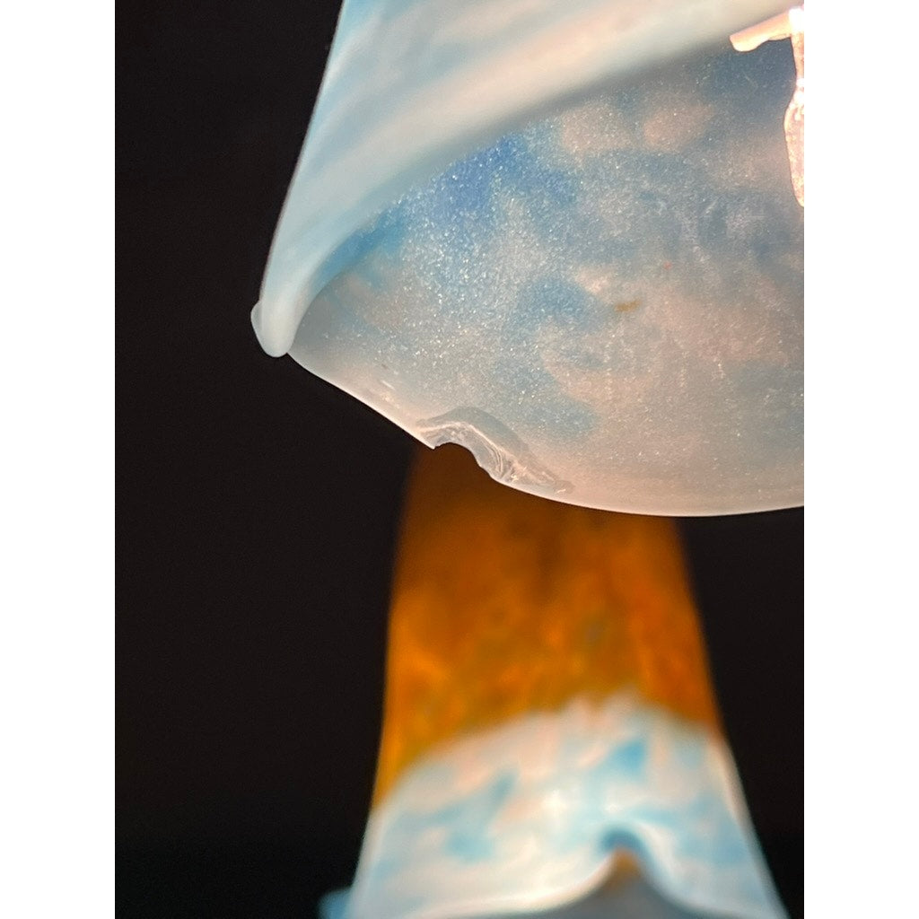 Close-up of a blue glass lampshade with a small chip, part of the Vintage Muller Frères Lunéville French Brass and Art Glass Four Light Chandelier. Another blue and amber Art Nouveau shade by Muller Frères Lunéville appears in the dark background.