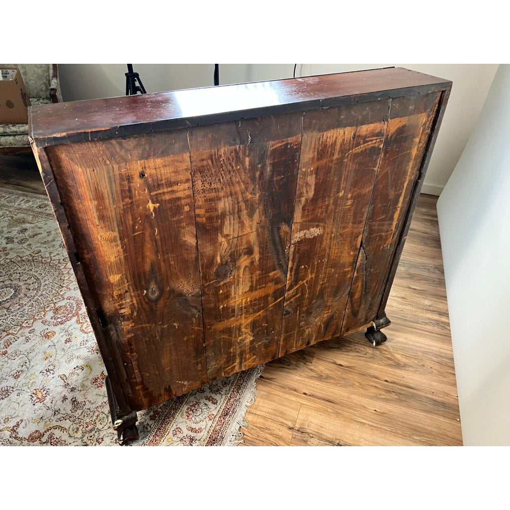 A solid cherry 18th Century New England Chippendale slant front desk, circa 1770–1790, with a dark finish stands on a wood floor near a patterned rug; its back reveals multiple wood panels and wheels on the bottom corners.