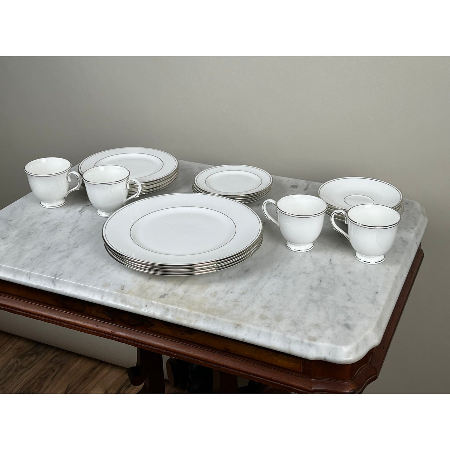The Lenox Vintage Lenox Federal Platinum Fine English Bone China Service for Four displays four dinner plates, four salad plates, and four teacups with saucers, elegantly arranged on a marble-top table against a neutral wall.