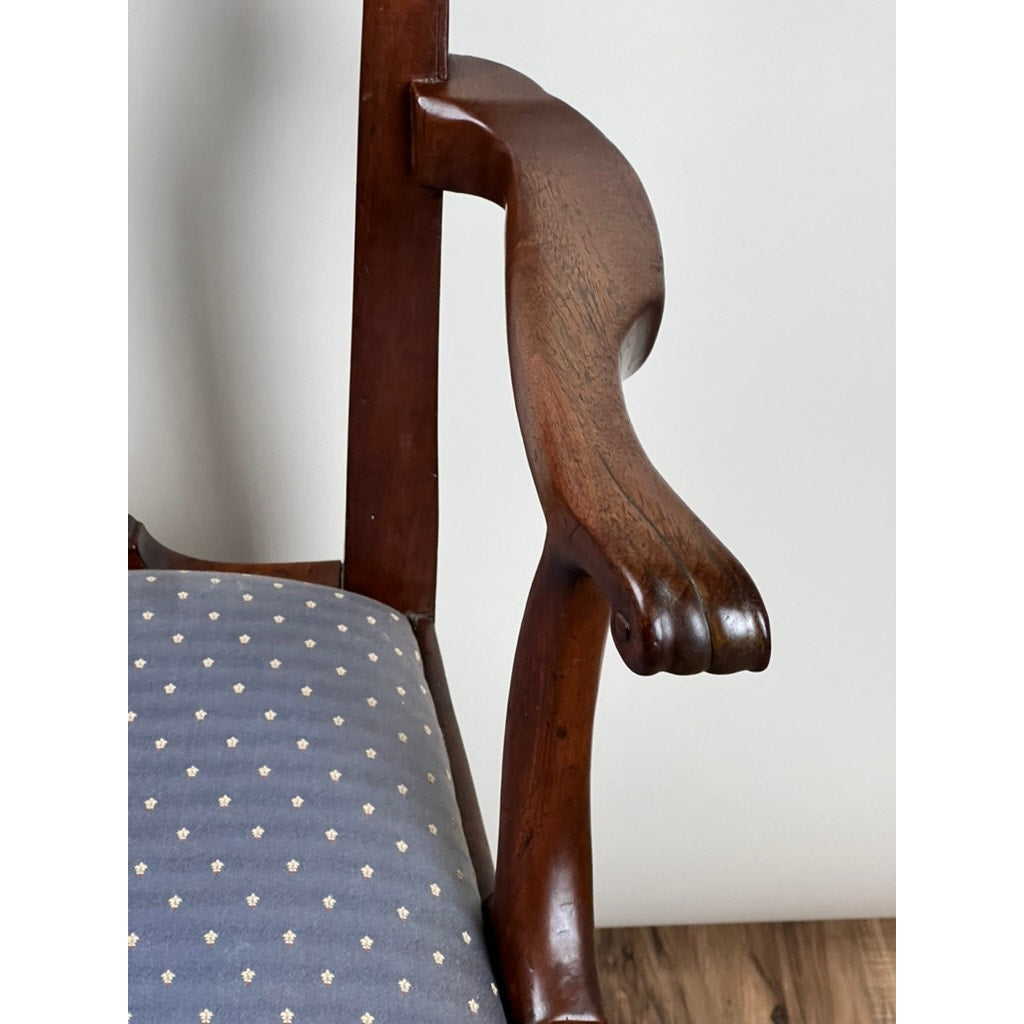 Close-up of an Antique Chippendale Walnut Open Arm Chair (c. Late 18th Century) with an animal paw carved arm and blue patterned upholstery, shown on a wooden floor against a light-colored wall. Brand: Unknown.