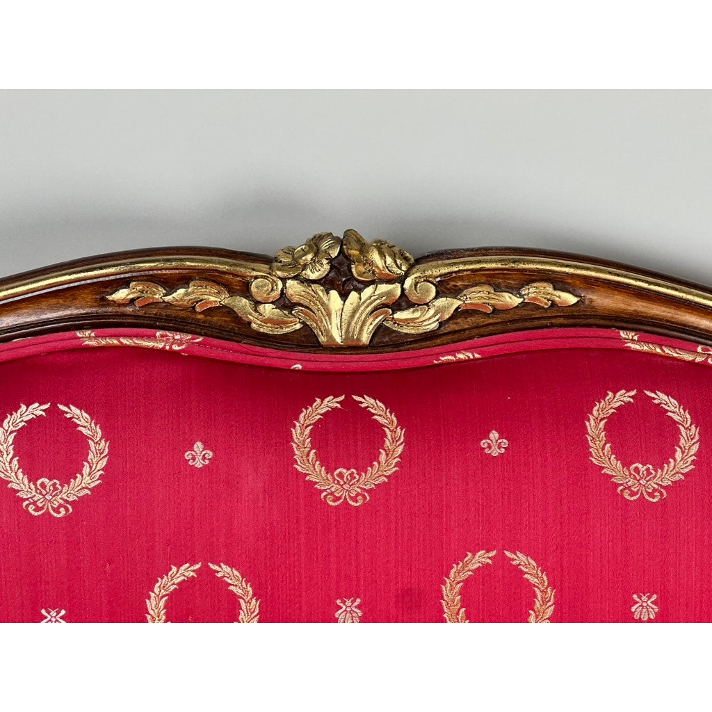 Vintage French Regency style custom upholstered settee featuring a giltwood frame with gold detailing and a red back adorned with a repeating laurel wreath pattern. Brand: None/Unknown.