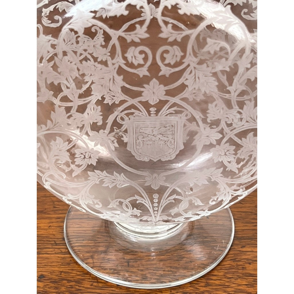 A Vintage Baccarat Crystal Decanter in the "Michelangelo" pattern for Martell Cognac (c. 1930), featuring intricate floral and vine engravings with a central crest, displayed on a wooden surface.
