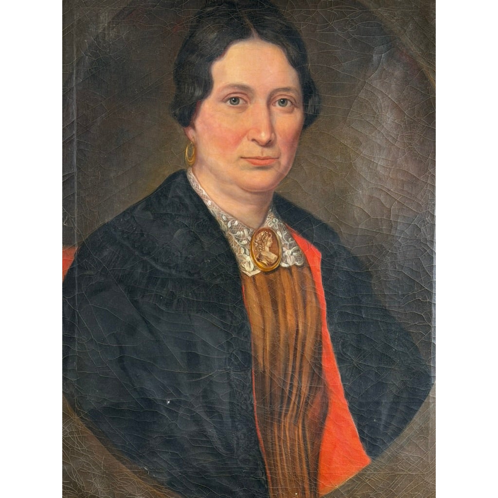 An oval mid-19th-century American oil portrait of a middle-aged woman from the Pair of American School Oil Portraits of a Gentleman and Lady, c. 1840–1860, wearing a black shawl over a tan dress, a lace collar, and a cameo brooch.