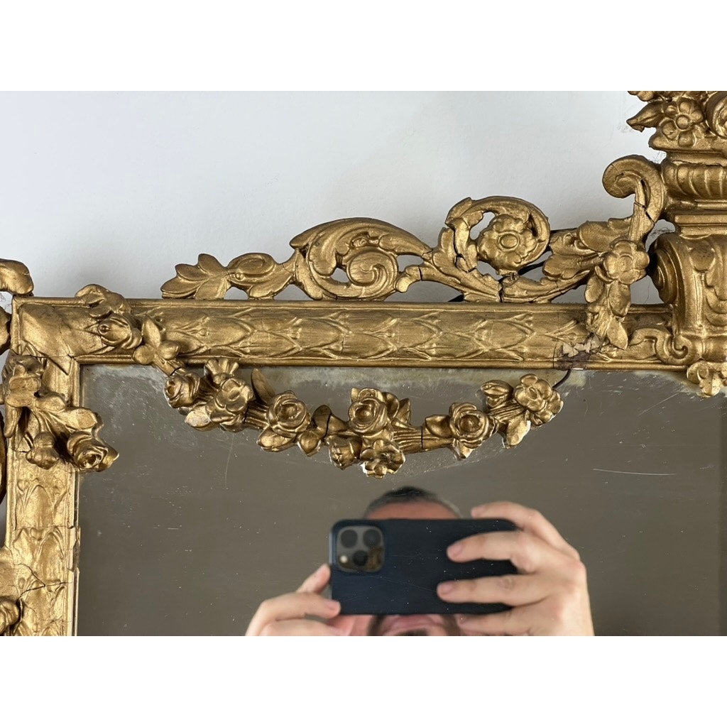 A person takes a photo with a smartphone in front of the Exceptional Antique Louis XV Style Three Panel Mirror Flanked by Images of Napoleon, its ornate gold frame partially reflecting their hands and part of their face at the bottom.