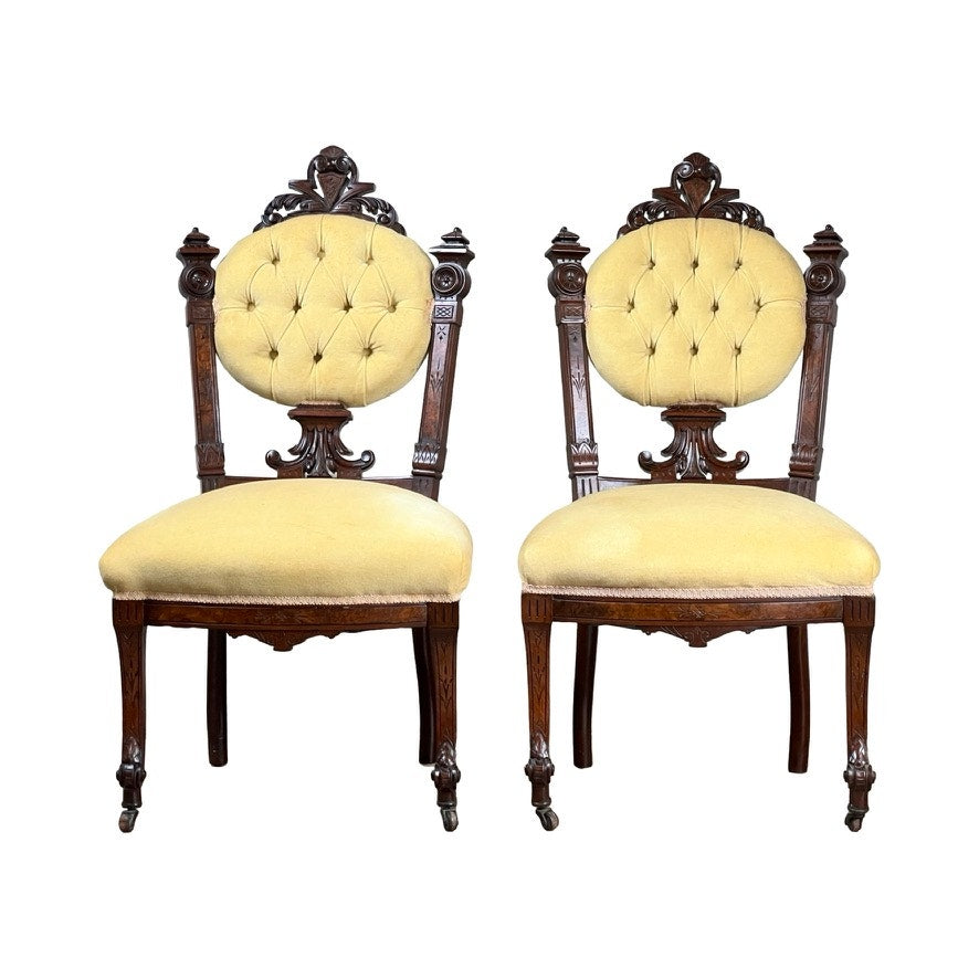 Fine antique pair of Renaissance Revival walnut side chairs attributed to John Jelliff, Newark c. 1880, featuring ornate carvings, round tufted yellow upholstered backs and seats, decorative legs, and intricate details.