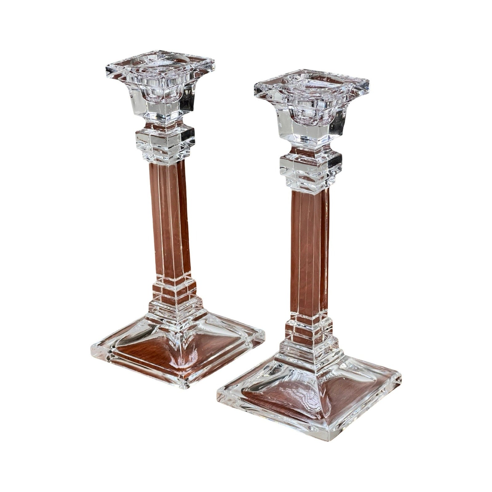 A vintage pair of Tiffany & Co. clear crystal candlesticks with square bases and decorative columns are displayed side by side on a white background.