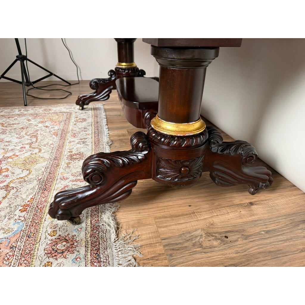 New York Classical Revival Carved Mahogany Double-Pedestal Library Table by Ernest F. Hagen, featuring gilded collars above scrolled, leaf-carved feet on casters.