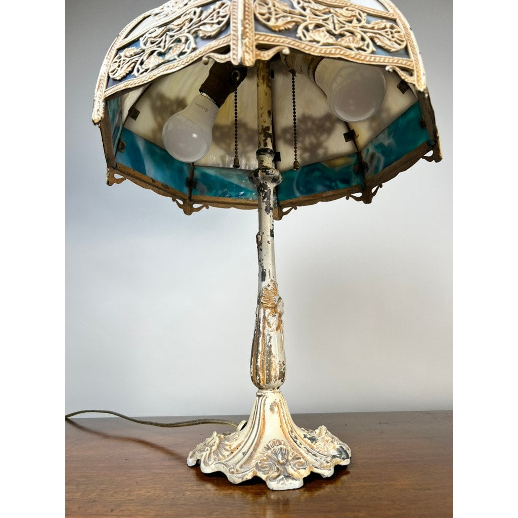 Vintage Art Nouveau Slag Glass Two-Light Table Lamp, c. 1935–1955, features an ornate metal base, stained glass shade, exposed bulbs, and antique finish. Brand: None/Unknown. Displayed on a wooden surface against a plain background.