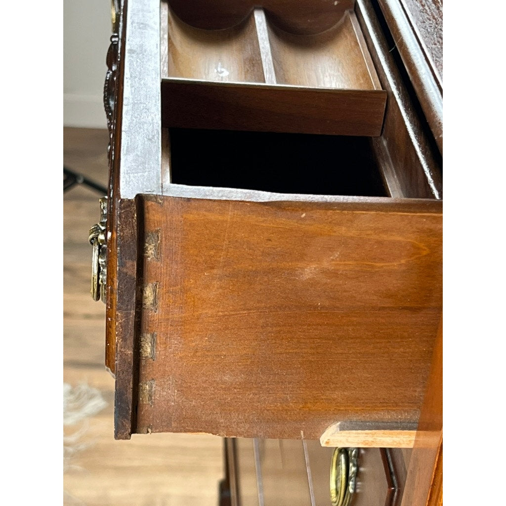 This Antique Depression Era Mahogany Two Over Three Chest of Drawers (c. 1930s) features dovetail joints, divided inner compartments, brass handles, and a polished finish. Shown partially open on a wooden floor against a white wall.