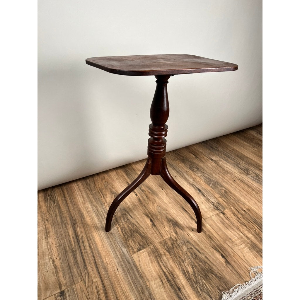 This Antique Federal Period Cherry Hepplewhite Candle Stand (mid 19th century) features a dark finish, rectangular top, single turned pedestal, and three curved legs—an elegant nod to classic Federal style. Brand: Unknown.