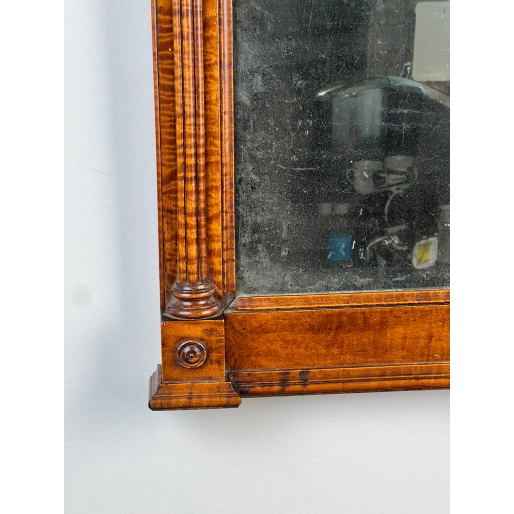 Close-up of the bottom left corner of a Fine Antique Federal Period Tiger Maple Two Panel Mirror c. 1820, showing ornate carved details and aged, speckled glass with faint background reflections. Brand unknown.