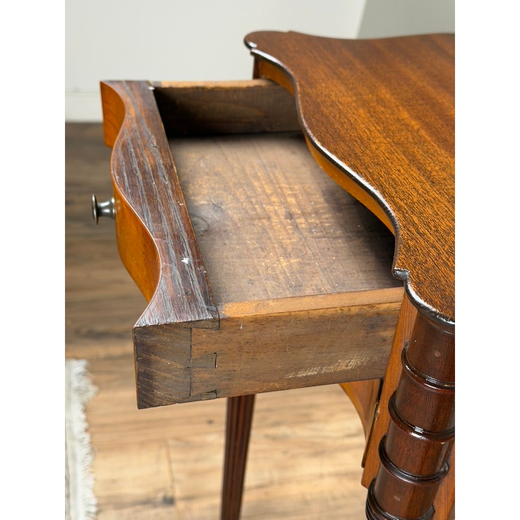 A Pair of American Classical Revival Mahogany Two-Drawer Work Tables with a serpentine edge and an open drawer revealing a shallow interior.