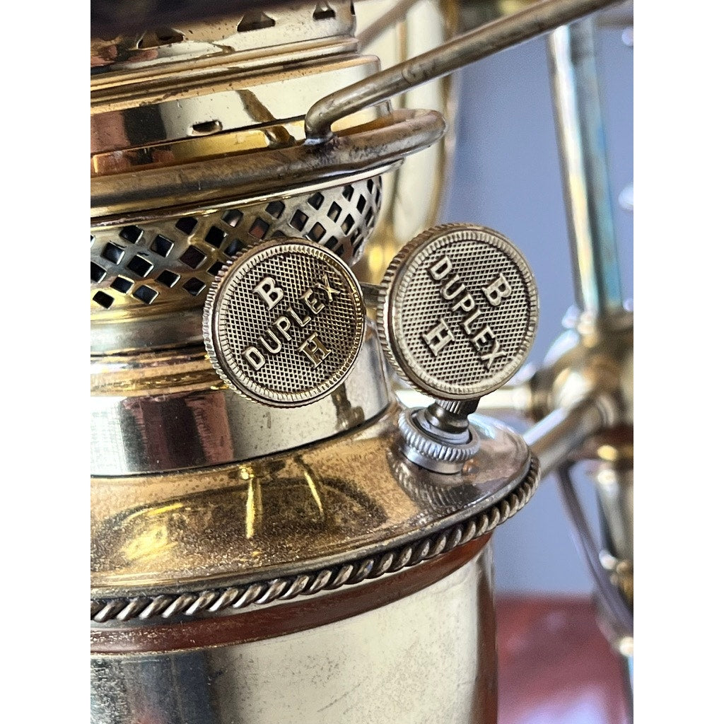 Close-up of two metallic knobs labeled B Duplex 15 and B Duplex H on an Antique Bradley and Hubbard Brass Double-arm Student Lamp with Carmel Shades, likely part of a classic Bradley and Hubbard design.