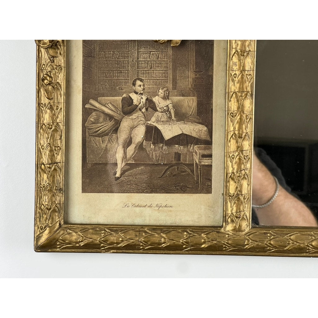 An exceptional antique Louis XV style three panel mirror, possibly French and flanked by images of Napoleon, features sepia artwork of a man and child studying a map in a book-filled study, with a hand’s reflection on the glass.
