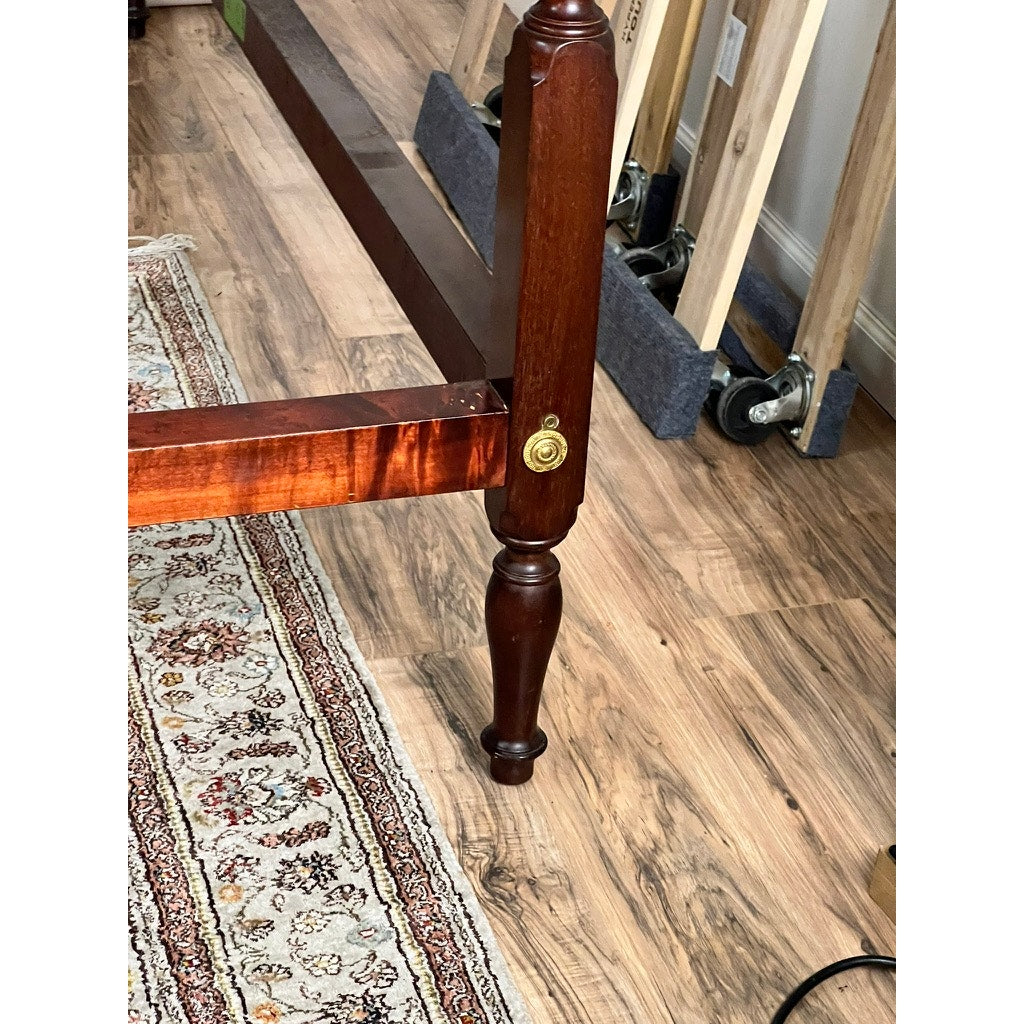 A Vintage Pair Centennial Solid Mahogany Twin Four Poster Beds c. 1940 stands on a wood floor near a patterned rug, with unassembled bed parts and wooden boards visible in the background.