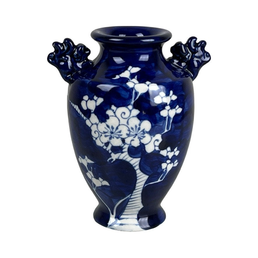 The Vintage Japanese Blue and White Floral Bud Vase showcases hand-painted white floral designs on dark blue ceramic, accented by two ornate dragon-shaped handles—a striking display of traditional blue and white pottery.